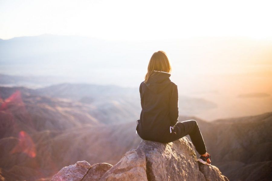 Mujer mirando un atardecer desde una montaña